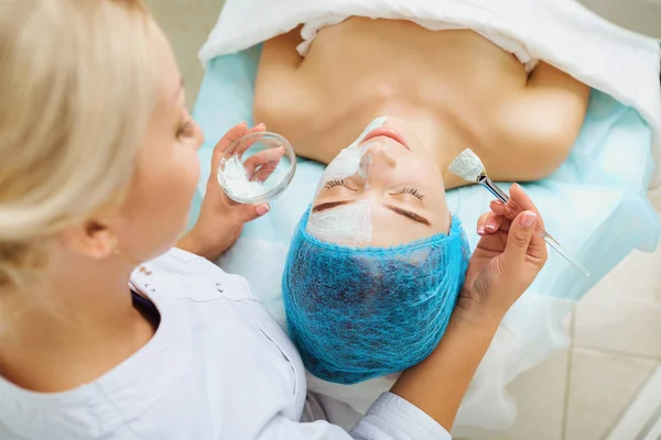 Cosmetologist makes beauty mask to a young woman. — Stock Photo, Image