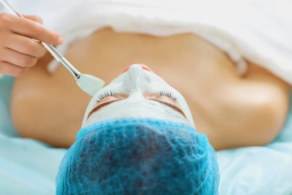 Cosmetologist makes beauty mask to a young woman.