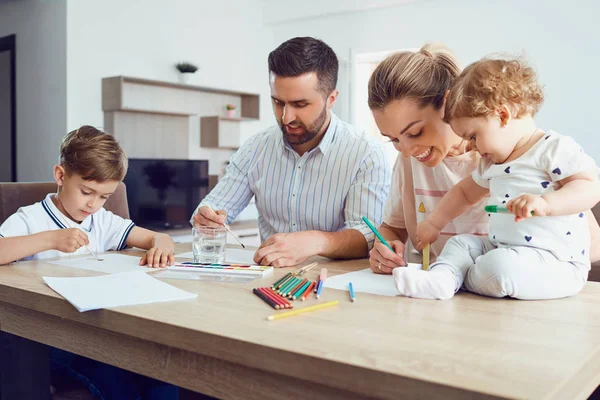 Keluarga bahagia menggambar lukisan di atas kertas di atas meja . — Stok Foto