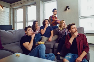 Bir grup arkadaşıyla birlikte eğlenceli yaşıyorsanız odasında Tv izliyor.