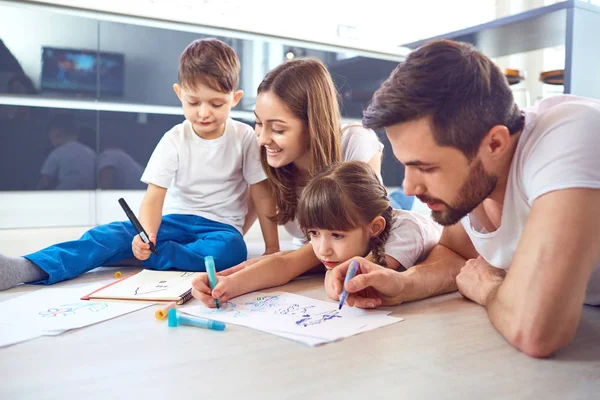 Uma família se baseia no papel deitado em seu tempo livre no chão . — Fotografia de Stock