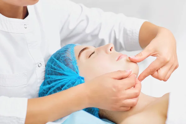 Kosmetolog gör ansiktsmassage till en ung kvinna. — Stockfoto