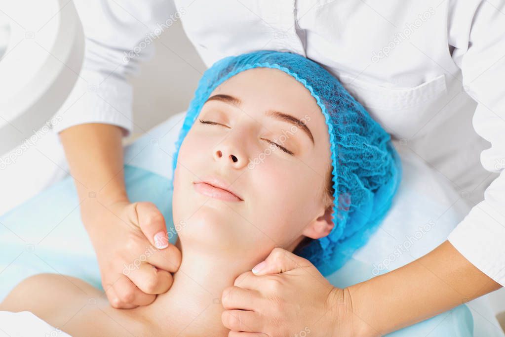 Cosmetologist makes facial massage to a young woman.