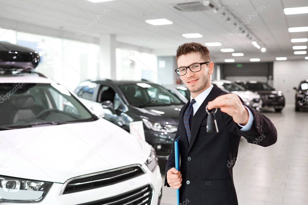 Il venditore di auto con le chiavi in mano nello showroom auto
.