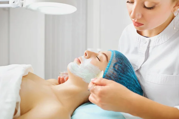 Cosmetologist makes beauty mask to a young woman. — Stock Photo, Image