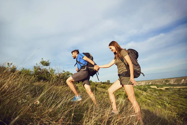 Un couple de voyageurs avec des sacs à dos aller sur une route . — Photo