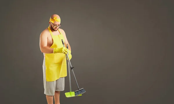 Funny fat cleaning man in an apron on cleaning.