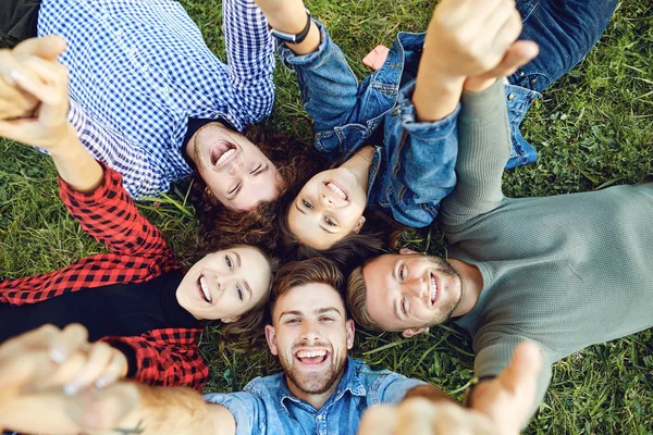 Vrienden liggen op het gras in het park. — Stockfoto