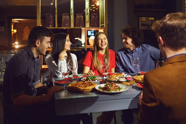 Um grupo de amigos comendo num jantar em um restaurante . — Fotografia de Stock