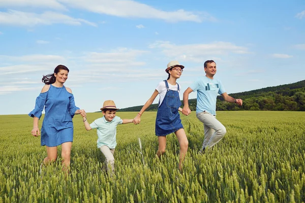 Šťastná rodina s úsměvem, běží na pole v přírodě — Stock fotografie