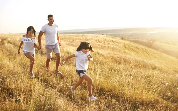 Щаслива сім'я, що гуляє на природі на заході сонця влітку . — стокове фото