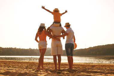 Mutlu aile birlikte gün batımında sahilde kucaklayan.