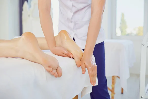 Терапевт масажує ноги клієнта, що лежить — стокове фото
