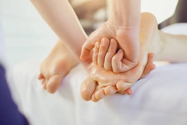 Terapeuta massageando os pés do cliente deitado — Fotografia de Stock