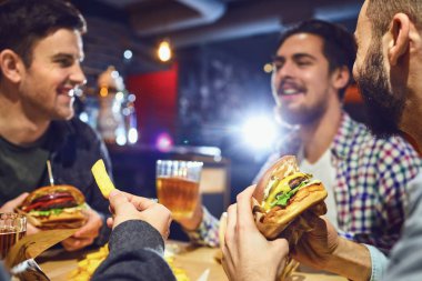 Mutlu arkadaş hamburger yemek, bir barda bira içmek.
