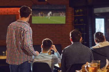 Bardaki TV'de futbol izlerken gençler.