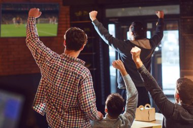 Bardaki TV'de futbol izlerken gençler.