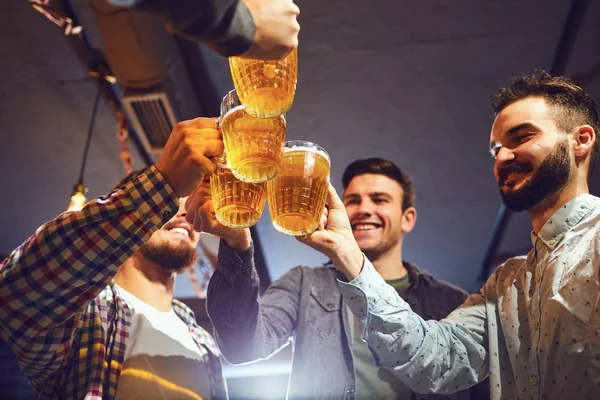 Young people clink glasses with beer in a bar.