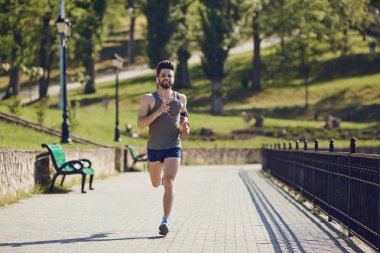Parka yol boyunca bir erkek atlet çalışır.