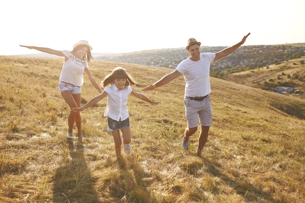 Szczęśliwa rodzina spaceruje w przyrodzie o zachodzie słońca w lecie. — Zdjęcie stockowe