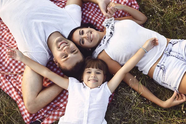 Divertida familia sonriendo tumbado en la hierba en la naturaleza en verano . — Foto de Stock