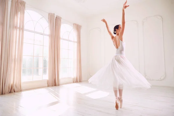 Молодая балерина танцует в белой студии — стоковое фото