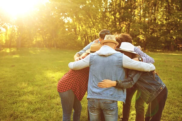 Een groep vrienden staat omarmen een picknick in het park. — Stockfoto