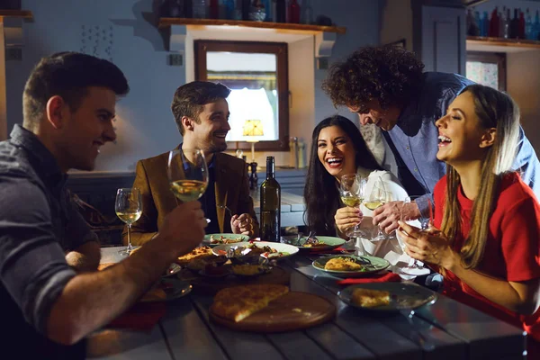 Jóvenes reunidos con amigos para cenar en un restaurante — Foto de Stock