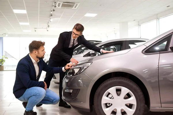 Cliente e venditore scelgono un'auto nello showroom — Foto Stock