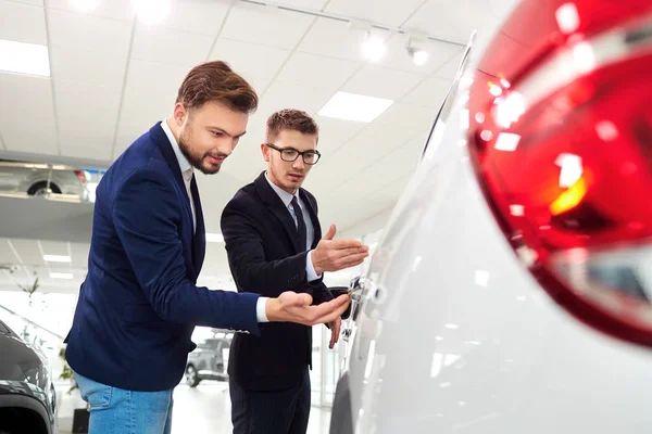 Rivenditore e cliente uomo compra una macchina nello showroom — Foto Stock