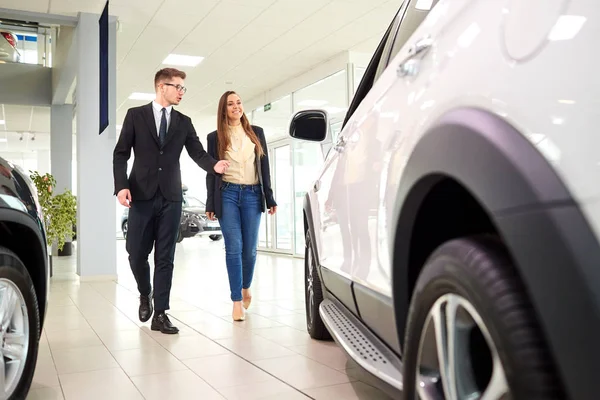 Girl and the salesman choose a car in the auto showroom Royalty Free Stock Images