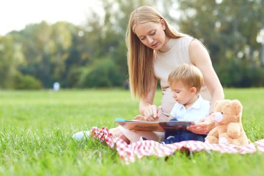 Çocuk ile anne parkta çim okur. 