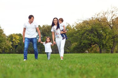 Çocuklu aile parkta yürüyor.