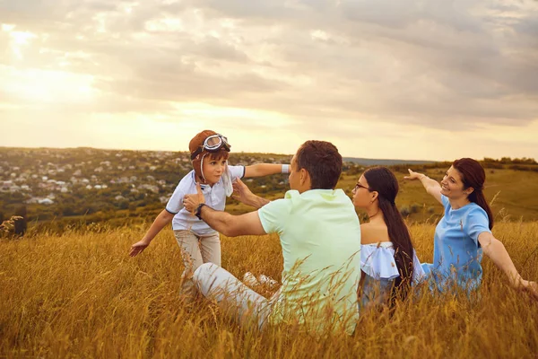 Mutlu aile doğada çimenlerin üzerinde günbatımında oynarken — Stok fotoğraf