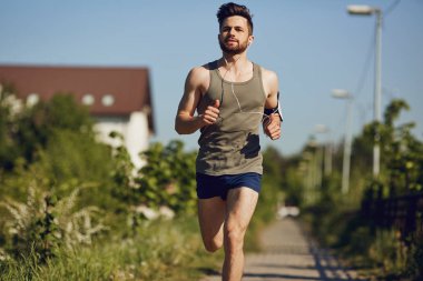 Parka yol boyunca bir erkek atlet çalışır.