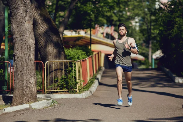 Un corredor masculino corre a lo largo del camino hacia el parque . — Foto de Stock