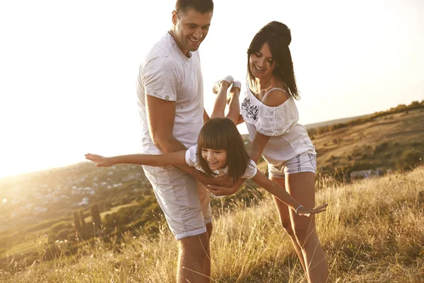 Gelukkige familie spelen op aard in de zomer bij zonsondergang. — Stockfoto