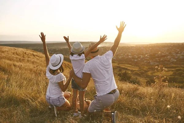 Ouders met een kind op zoek om te ontspannen bij zonsondergang op de zomer natuur. — Stockfoto