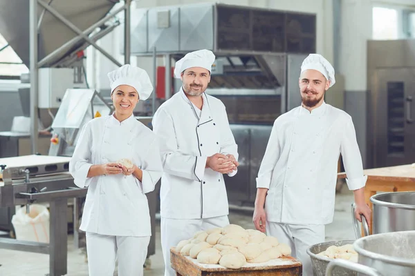 Un gruppo di panettieri sorride al panificio — Foto Stock