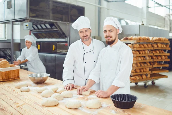 Los hombres panaderos en el lugar de trabajo en la panadería — Foto de Stock