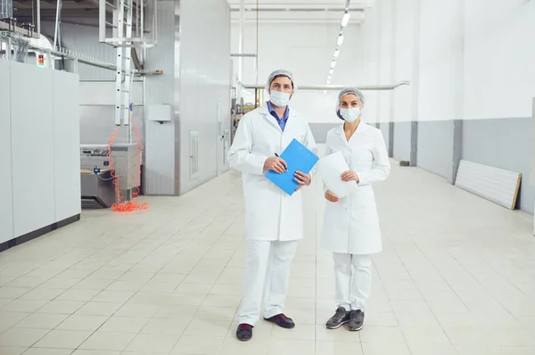 Pessoas tecnólogos em máscaras na fábrica de alimentos . — Fotografia de Stock