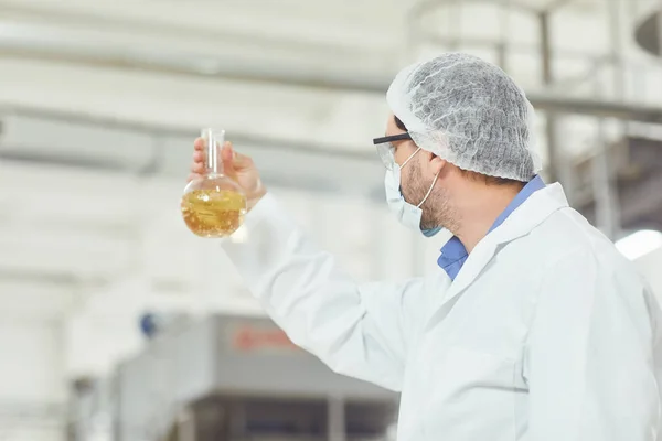 O tecnólogo analisa o líquido no balão sobre a produção . — Fotografia de Stock