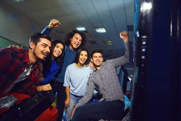 A group of friends playing arcade machine. — Stock Photo, Image