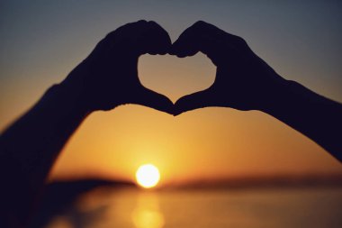 Kalp gün batımı üzerinde eller tarafından yapılmış.