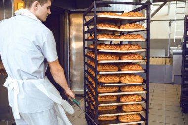 Fırıncı fırın fabrikada ekmek ile bir tepsi iter.