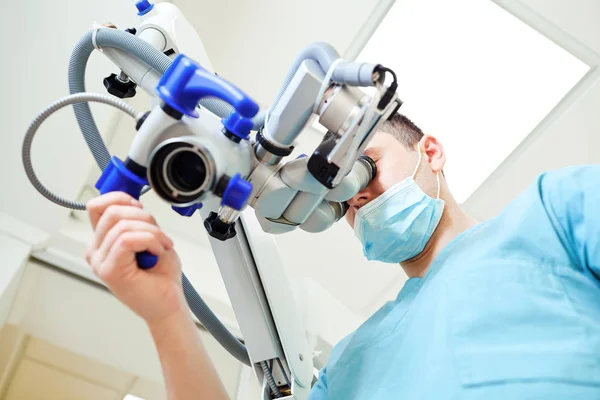 Un dentiste qui regarde au microscope dans un cabinet dentaire — Photo