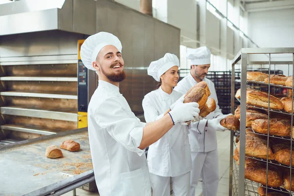 Baker man houdt vers brood in een bakkerij. — Stockfoto