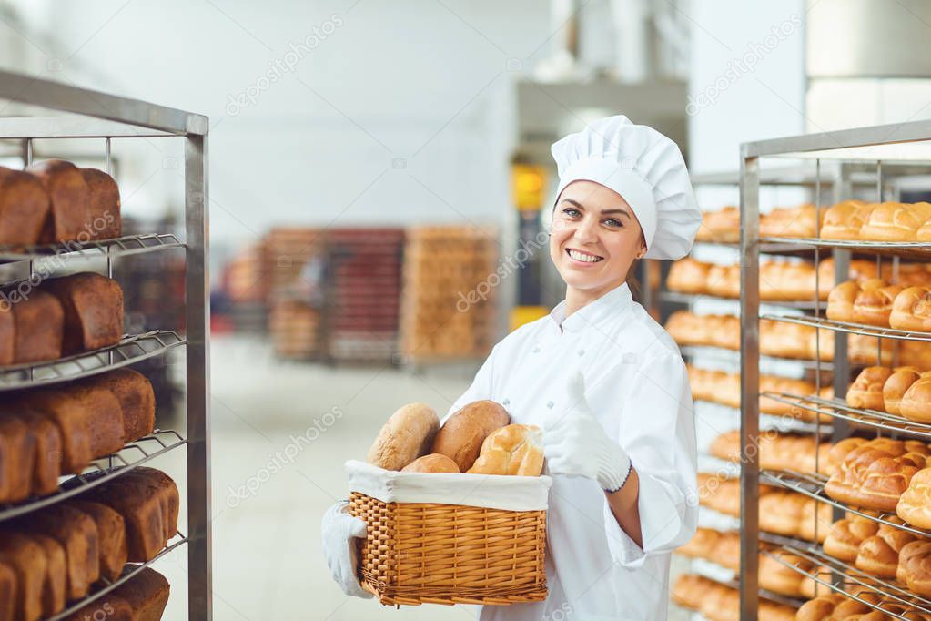 A baker woman holding a basket of baked in her hands at the bakery