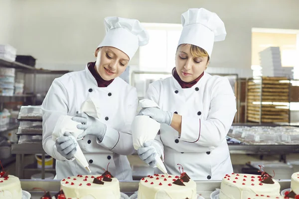 Un pasticcere spreme la crema liquida da un sacchetto di pasticceria . — Foto Stock