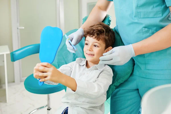 男孩的孩子和牙医正在检查镜子里的牙齿. — 图库照片